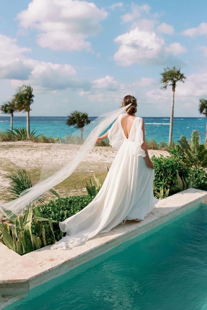 Bride walks alongside of pool on Bahamas private island