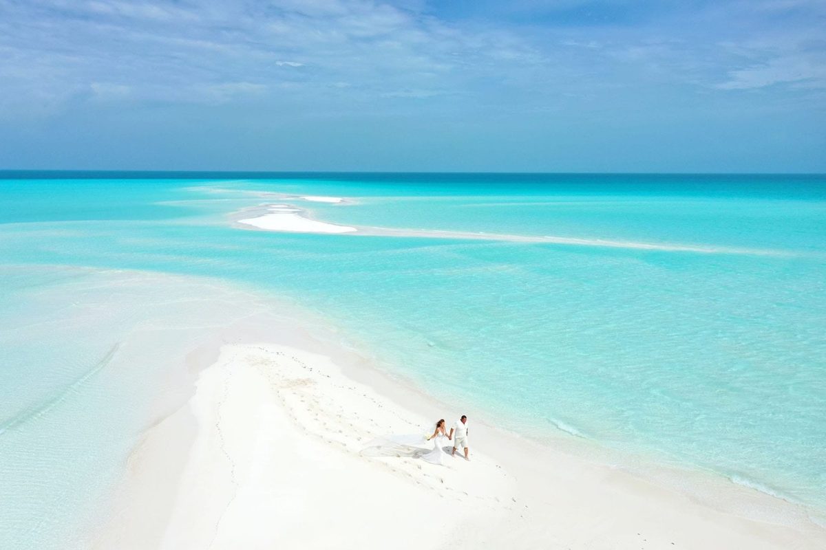 Bride and groom on a sandbar with clear blue water surrounding them